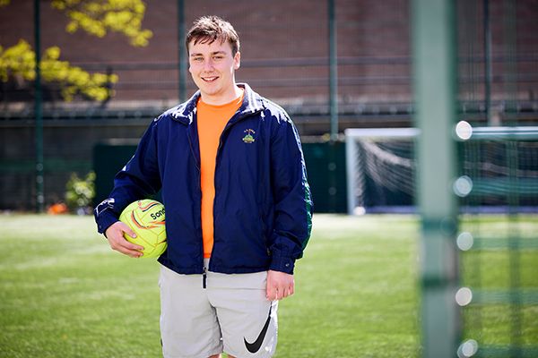 Logan Donoghue smiling at the camera standing on a football pitch