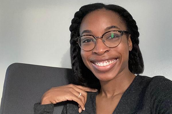 Alumni volunteer, Michelle Iyalla Harry, smiling at the camera wearing a black top and glasses.