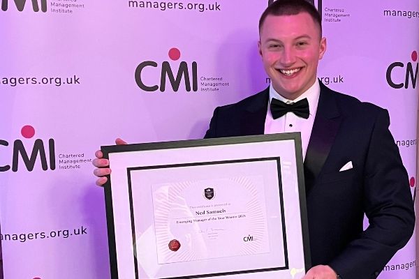 Person holding framed award at CMI event backdrop.