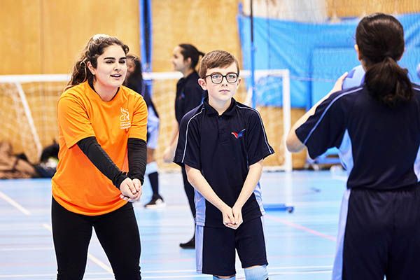 Nilu teaching two students volleyball.