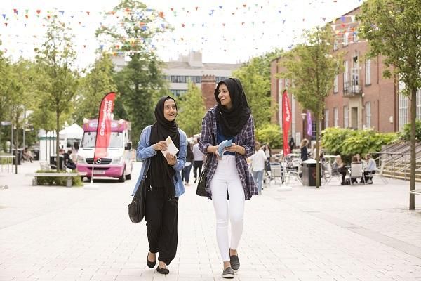 Two students wearing black headscarves walk together down the precinct outside Leeds University Union.