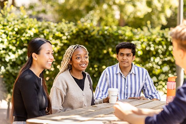 Three students sat outside in the sunshine.