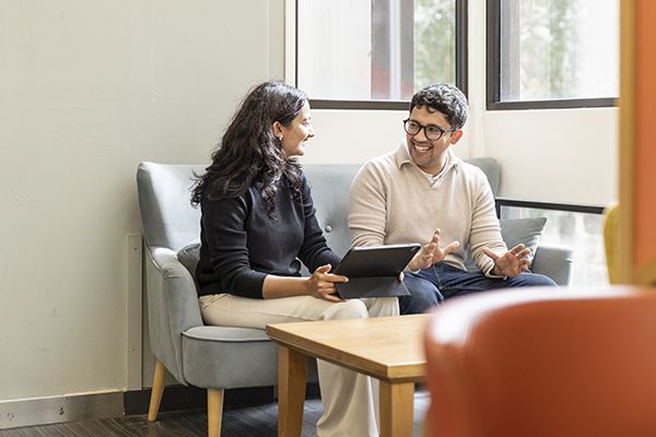 Two postgraduates chatting by a bright window.
