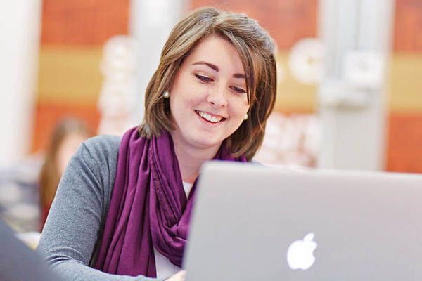 An online learner using a laptop in a library.