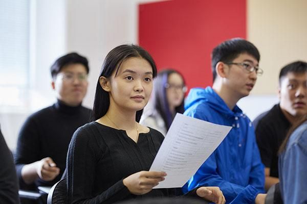 A pre-sessional English student holding a piece of paper.