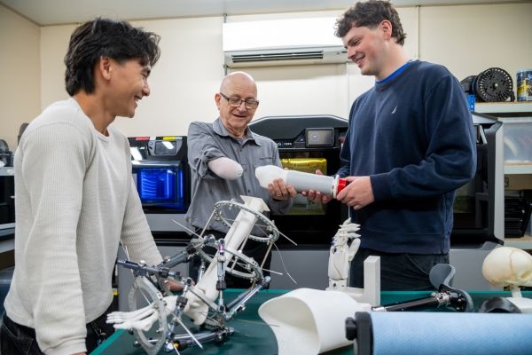 Two engineering students help a client with a prosthetic arm