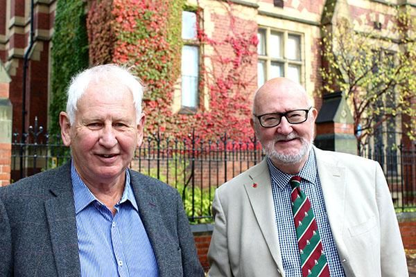 Two Leeds alumni standing outside the Great Hall in autumn