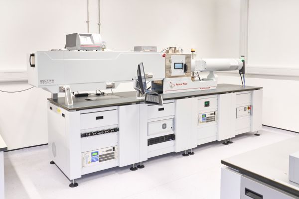 The equipment, which consists of a large rectangular section, a small metal chamber door, and a horizontal cylinder on the top. The base has cooling apparatus, a server and power supply. A user console and computer apparatus are attached.