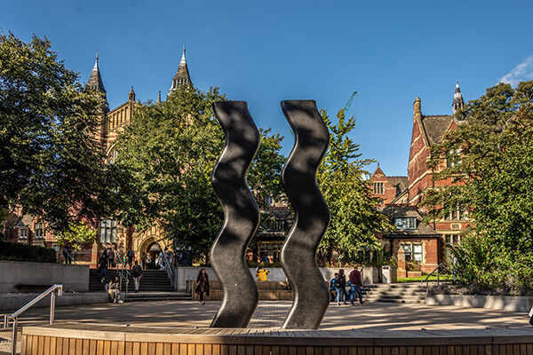 Students walking and sitting around the Sign for Art sculpture outside the Great Hall