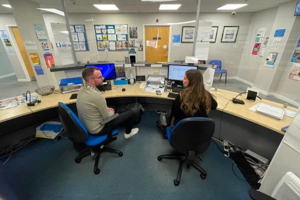 Two reception staff sitting at the desk in front of computer screens