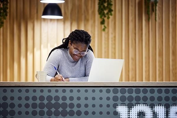 A student sat in a cafe on campus working at a laptop.