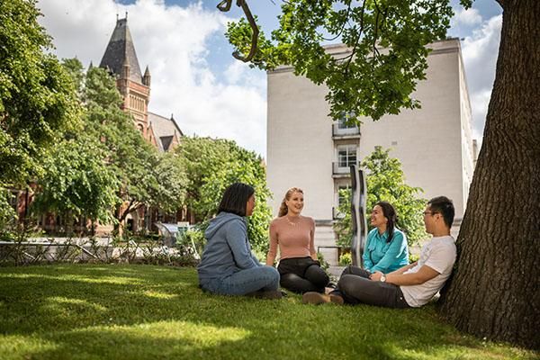 A group of students sitting on grass with the Great Hall in the background