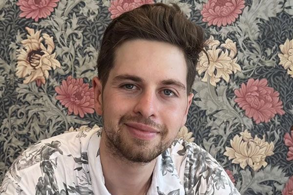 Theodor smiling in front of a floral pattern.