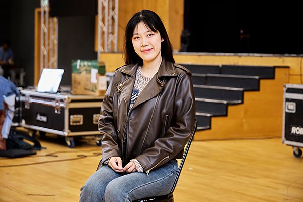 Tianyue Gai sitting smiling at the camera in a hall