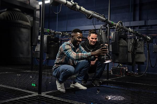 A student and a theatre technician rigging a light.