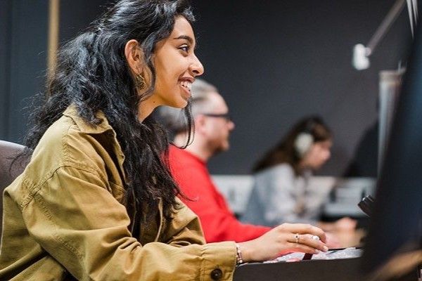 A portrait of Henna sat in a recording studio with other students.