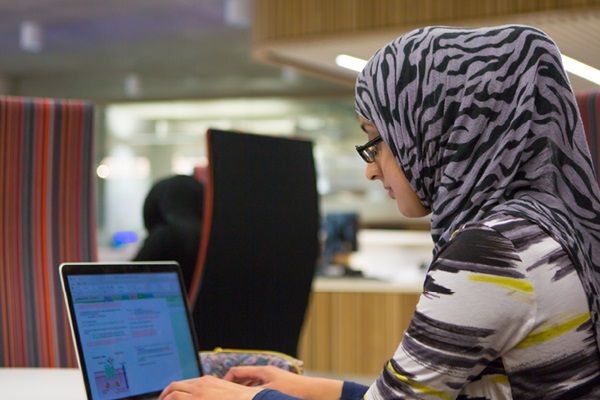 A student sat inside a study space using a laptop