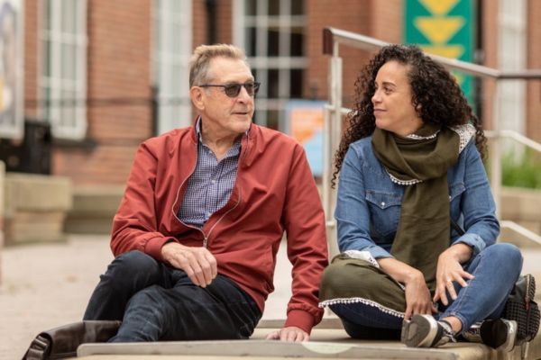 Two mature students sitting outside Leeds University Union on campus.