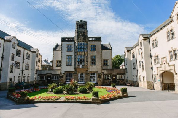 Devonshire Hall student residences, grand buildings in a courtyard with an area of manicured lawn and plants.
