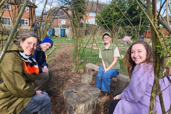 Four people sat in a community garden in Leeds, smiling.