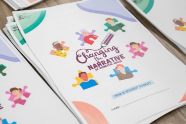 A pile of printed reports entitled 'Changing the narrative of domestic abuse'.