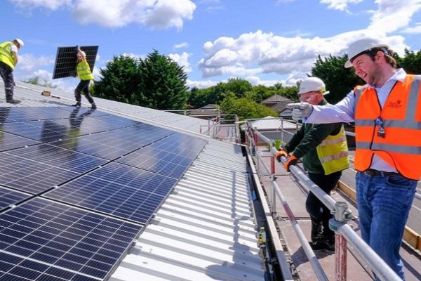 Solar panel installers at work on a large roof.