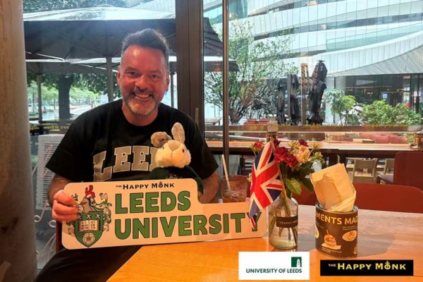 Jeremy Sargent, smiling, holding a sign that reads Leeds University.