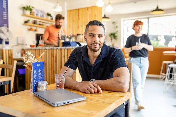 An online student sat in a cafe, with their laptop on their table.
