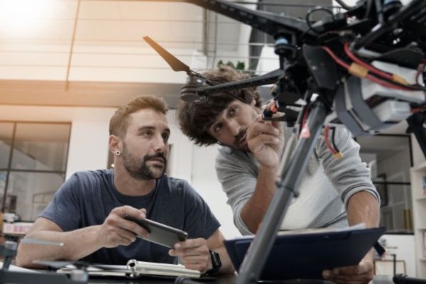 An engineer and a technician working together on a drone in an office