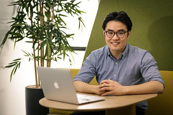 A student sits at a table with a laptop in front of them