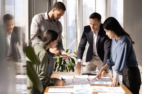 Four people stood in a business environment planning out a project.