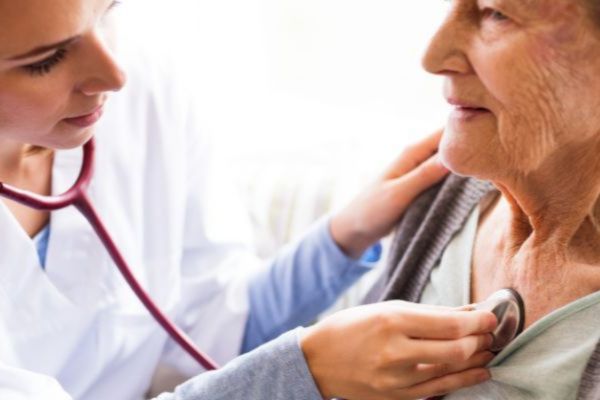 Doctor or nurse using a stethoscope to listen to an elderly patient's heart.