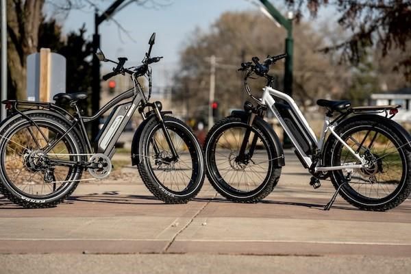 Two e-bikes stood facing each other on a pavement
