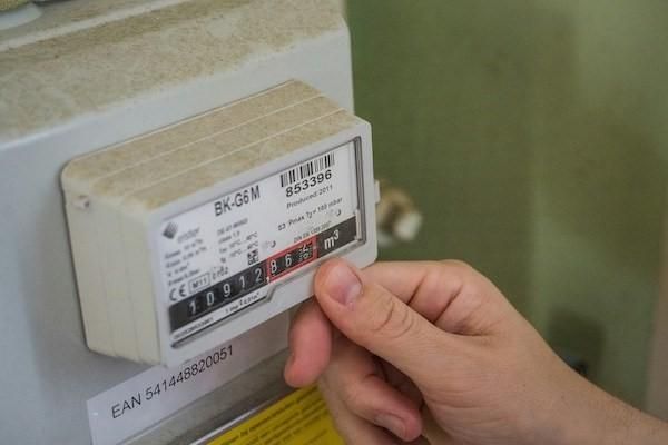 Close up of a hand looking at an analogue electricity meter number