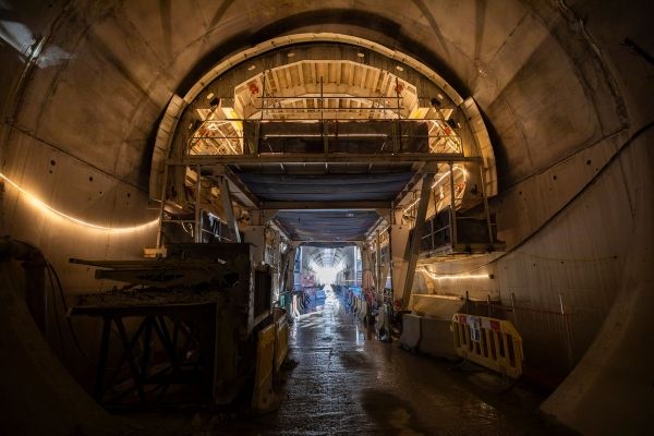 Large illuminated construction tunnel with workers in distance