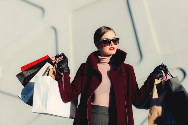 Well-dressed person holding designer shopping bags in each hand.