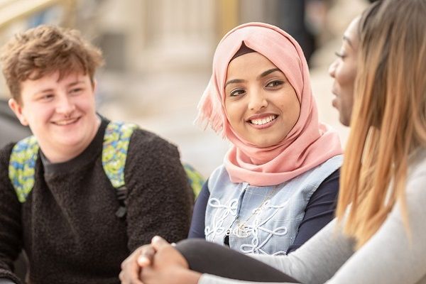 Three students sat on Parkinson Building steps chatting and smiling