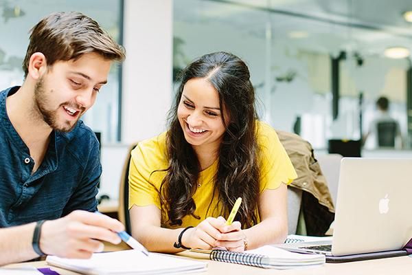 Two postgraduate students sitting at a desk studying together