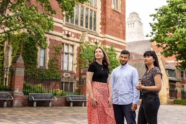 Three students in conversation outside the Great Hall. The Parkinson Building tower can be seen in the background.