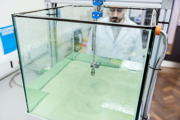 A scientist observes the effect of a jet of water into a bed of sand