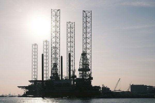 Silhouette of an oil rig against a blank sky