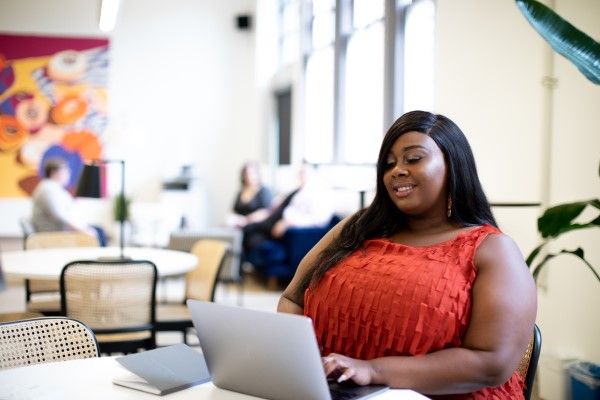 A person working on a laptop at a table in a social space.