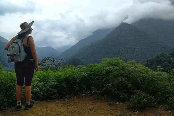 A woman wearing a hat looking at mountains surrounded by mist and clouds