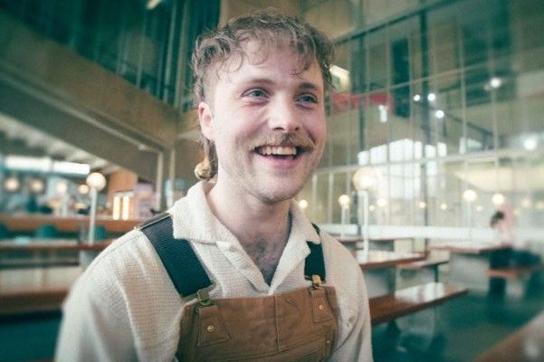 A student sits smiling in a coffee shop.