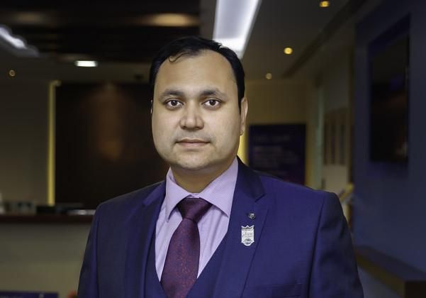 Leeds alumni community member, Sandeep Kinge, wearing a suit and purple shirt and tie.