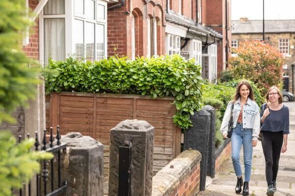 Two students walking down a street with terraced houses on