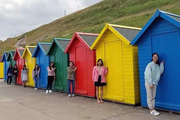 Leeds International Summer School students standing in front of beach huts