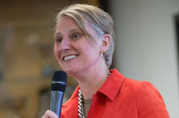 Alumni volunteer, Liza Kellet, wearing an orange jacket and speaking into a microphone.