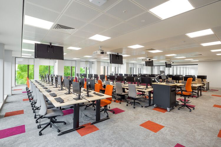 A large room with many long desks and many computer monitors.