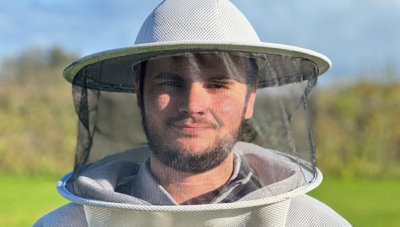 Harry Simpson is pictured wearing a beekeeping hat with veil.